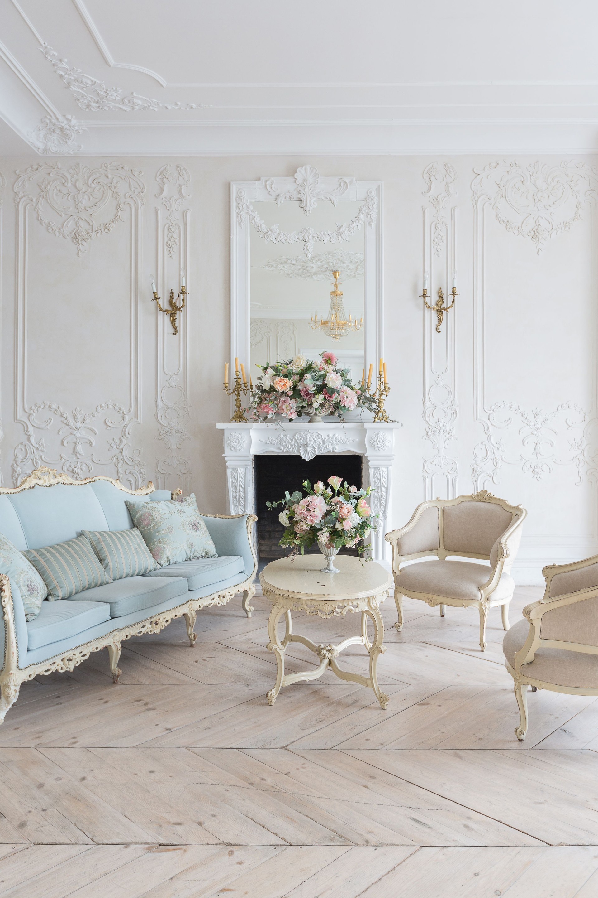 luxurious light interior in the Baroque style. A spacious room with a road chic beautiful furniture, a fireplace and flowers. plant stucco on the walls and light wood parquet