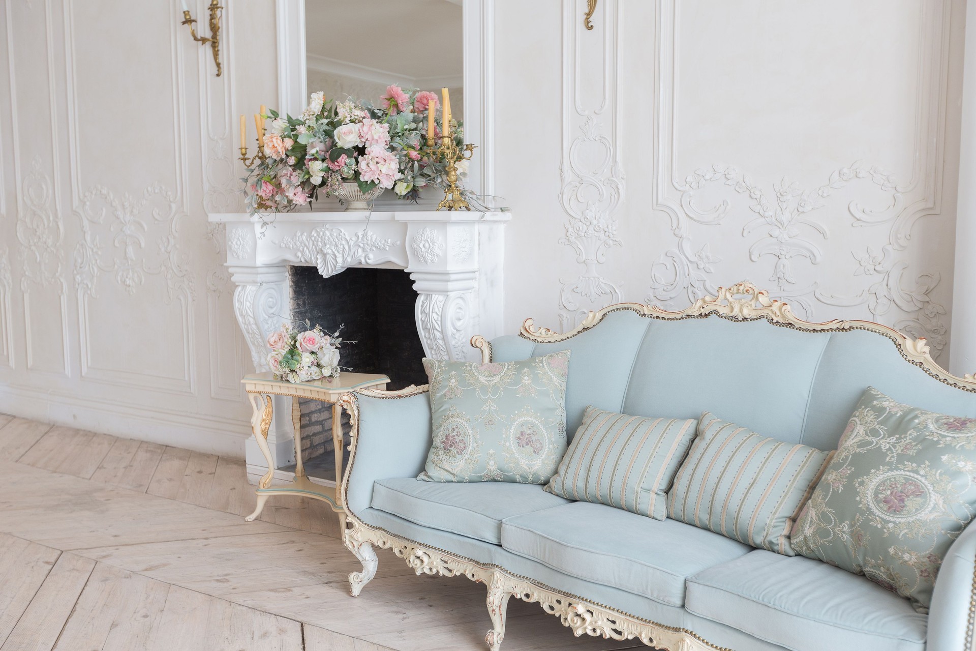 luxurious light interior in the Baroque style. A spacious room with a road chic beautiful furniture, a fireplace and flowers. plant stucco on the walls and light wood parquet