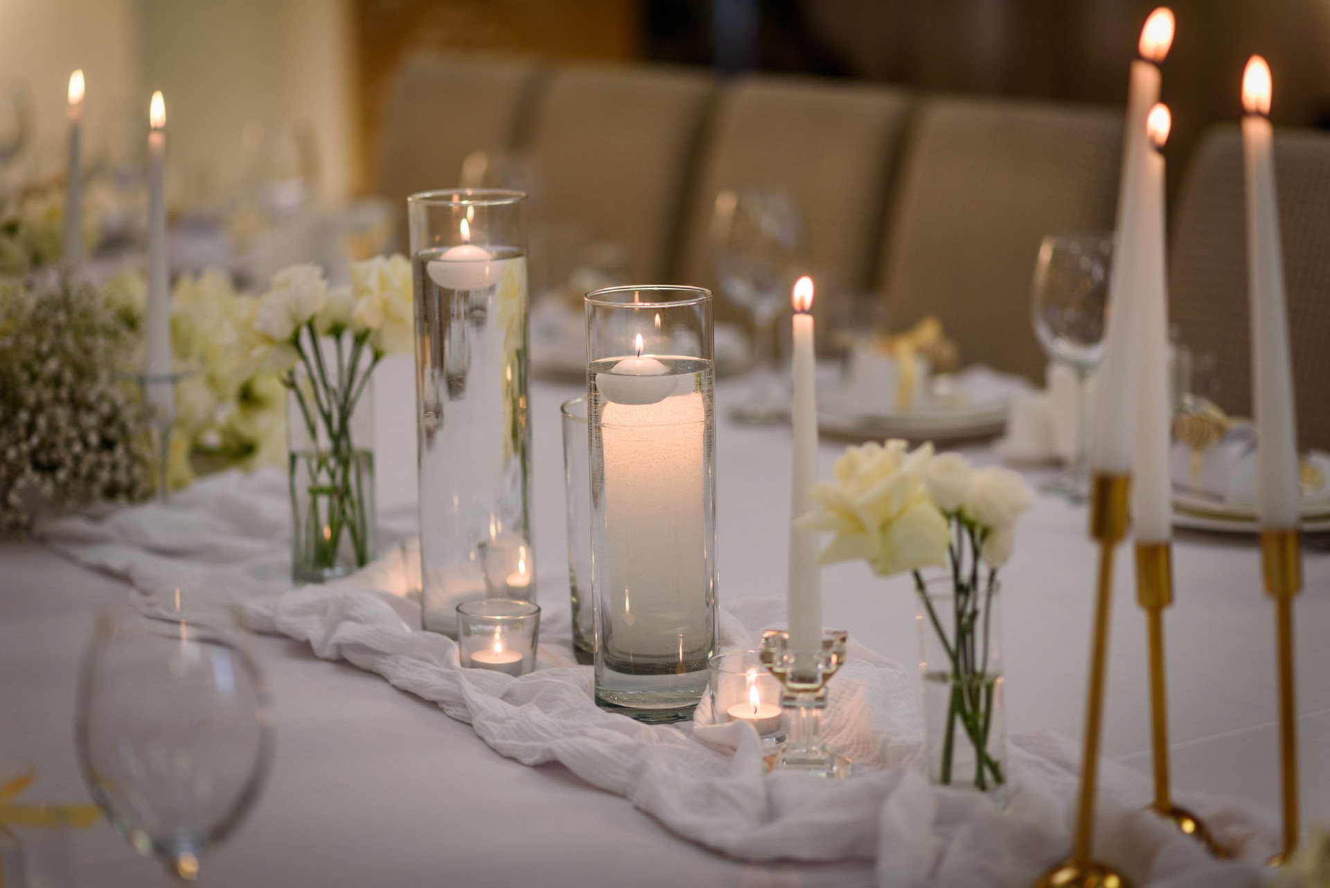 Table setting, serving closeup. Wedding setup detail. Banquet decoration in hall restaurant. Luxury reception. Festive table covered tablecloth, decorated composition flowers and candles in party area