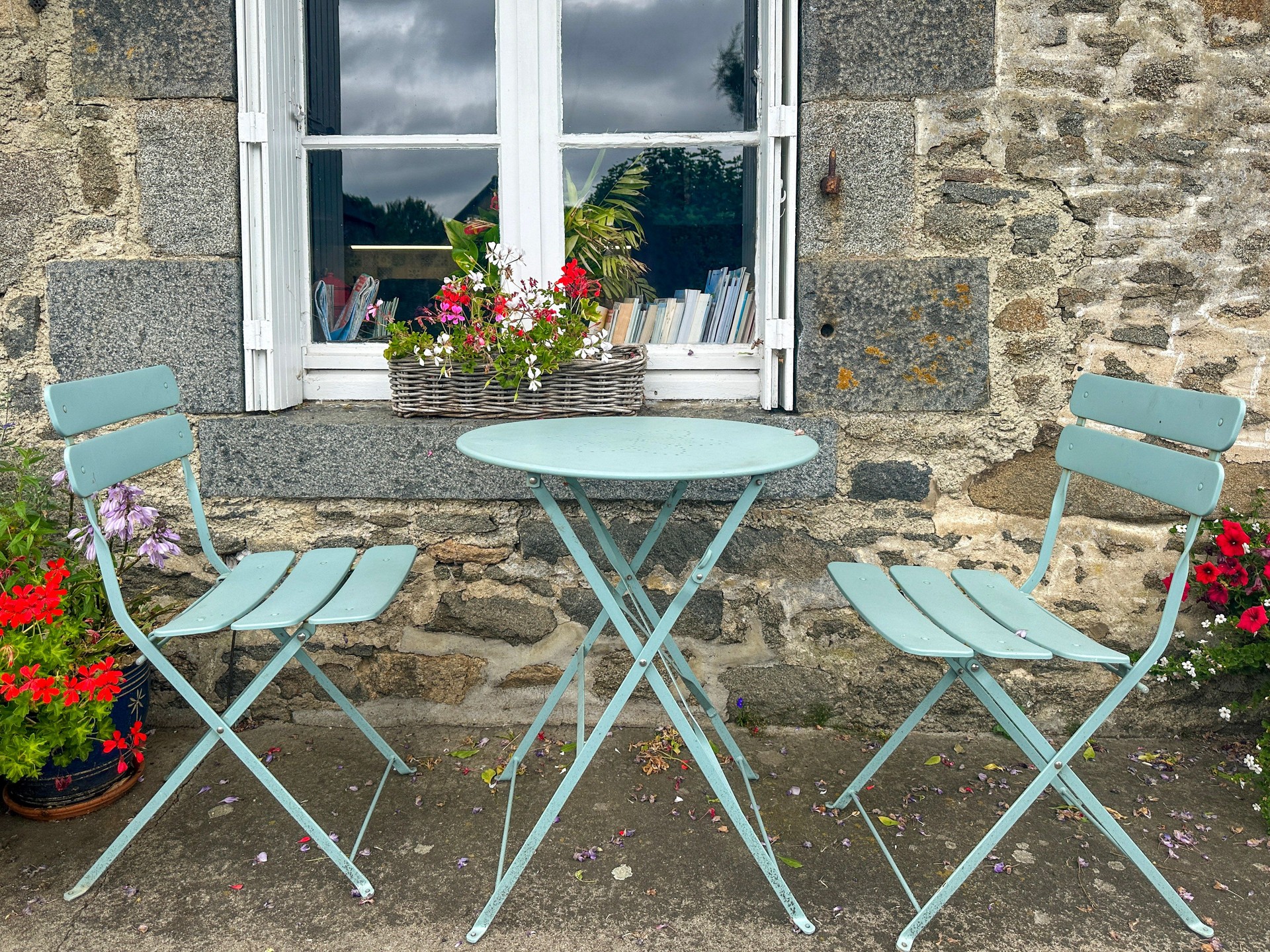 Metal tea table and chairs in blue-green color near the window