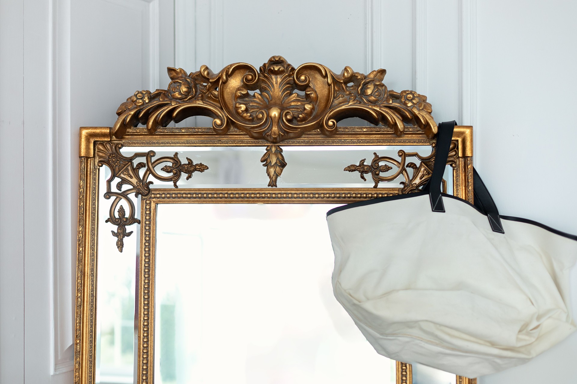 Antique baroque brass gold frame and mirror. Beautiful large vintage mirror with decorative frame. Close up of ancient mirror with bag hang on wall. Golden vintage mirror isolated on white background.